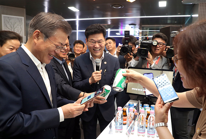 President Moon Jae-in (left) learns how to open a bank account on a smartphone at Seoul City Hall on Aug. 7. (Cheong Wa Dae)